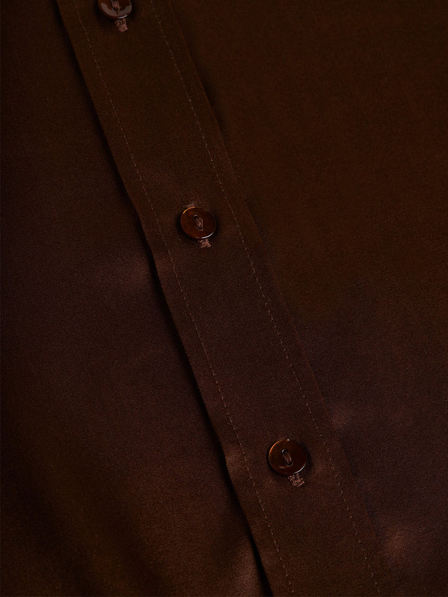 Close-up of the L'Agence Dani Blouse in Hot Fudge, a dark brown silk button-down shirt featuring a row of buttons along the placket, adding an iconic touch to your wardrobe.