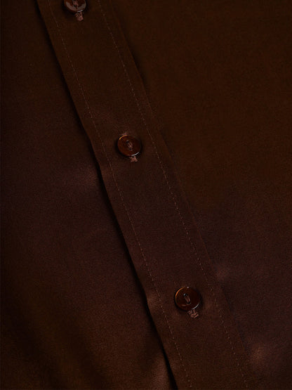 Close-up of the L'Agence Dani Blouse in Hot Fudge, a dark brown silk button-down shirt featuring a row of buttons along the placket, adding an iconic touch to your wardrobe.