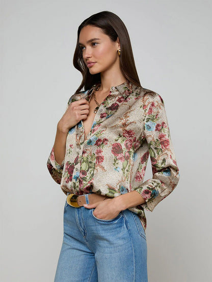 A woman models the L'Agence Dani Blouse in Multi Floral Tapestry with rolled sleeves, styled with light blue jeans against a plain background.