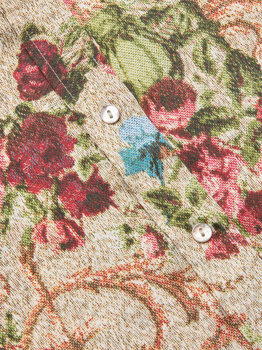 Close-up of the L'Agence Dani Blouse in Multi Floral Tapestry, showing red, green, and blue floral print fabric with a folded section and two silver-colored buttons.