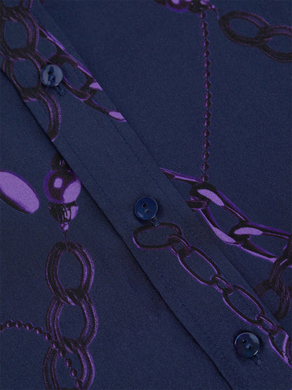 A close-up of the L'Agence Dani Blouse in Midnight/Purple Sketch Chain, featuring a navy blue silk fabric decorated with a pattern of purple chains and designed with three-quarter length sleeves.