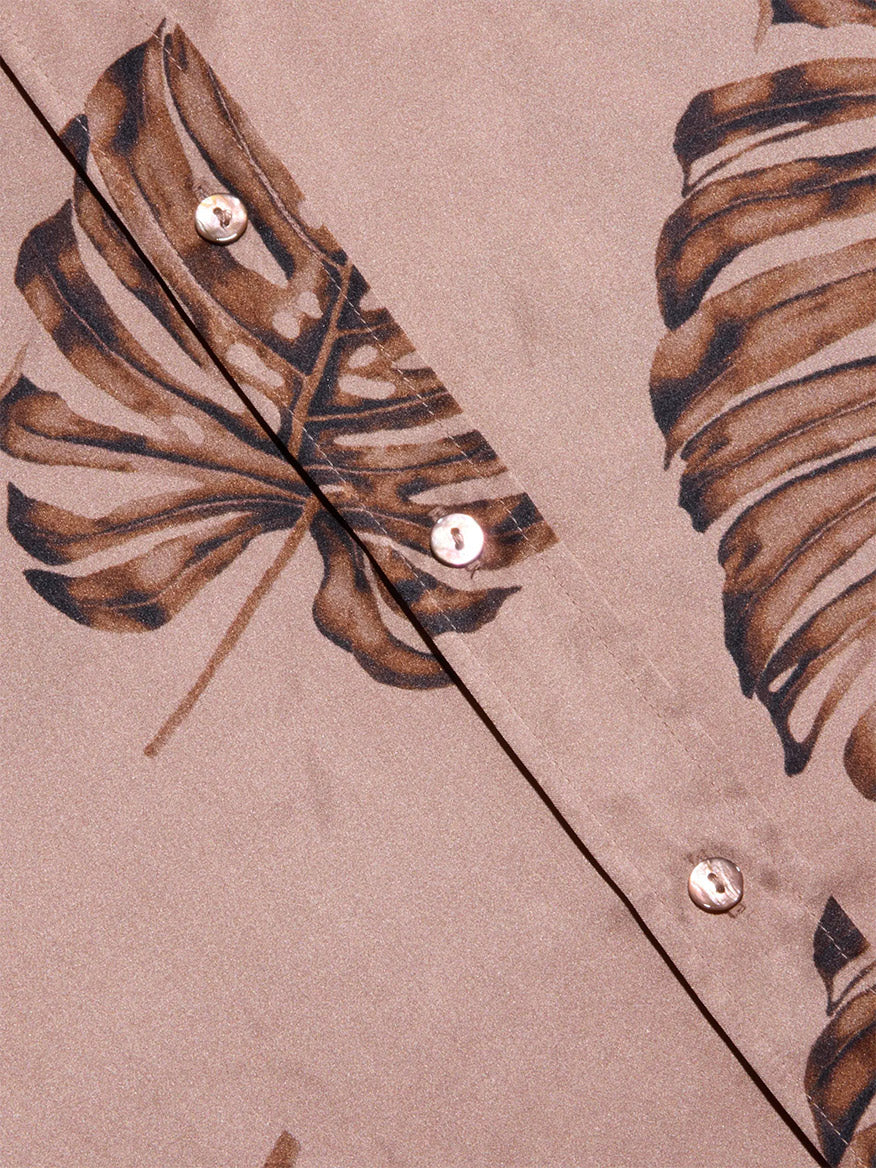 Close-up of the L'Agence Dani Blouse in Hazelnut Multi Large Palm, showcasing a brown palm leaf print and two white buttons along a diagonal seam.