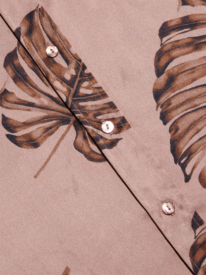 Close-up of the L'Agence Dani Blouse in Hazelnut Multi Large Palm, showcasing a brown palm leaf print and two white buttons along a diagonal seam.