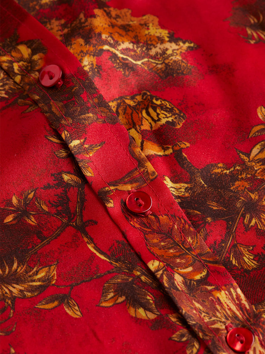 Close-up of the L'Agence Emmy Sleeveless Blouse in High Risk Red Multi Jungle Toile, showcasing a nature-themed pattern with tigers and leaves on vibrant red silk, accented by matching red buttons.