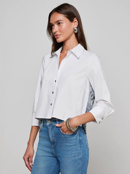 A woman wears the L'Agence Fawn Panther Print Shirt in Ivory Multi Floral Panther Scarf with blue jeans, standing against a plain gray background.