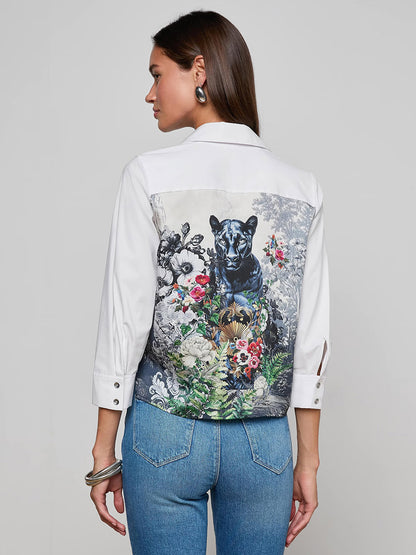 Woman stands with her back to the camera, wearing the L'Agence Fawn Panther Print Shirt in Ivory Multi Floral Panther Scarf, showcasing its detailed floral panther print on the back and paired with blue jeans.