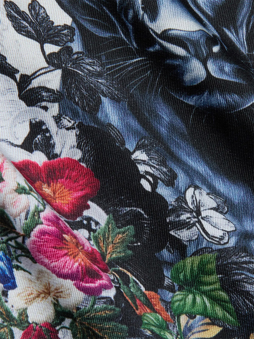 Close-up of the L'Agence Fawn Panther Print Shirt in Ivory Multi Floral Panther Scarf, showcasing textured fabric with a colorful floral panther motif and multicolored flowers and leaves on a dark background.