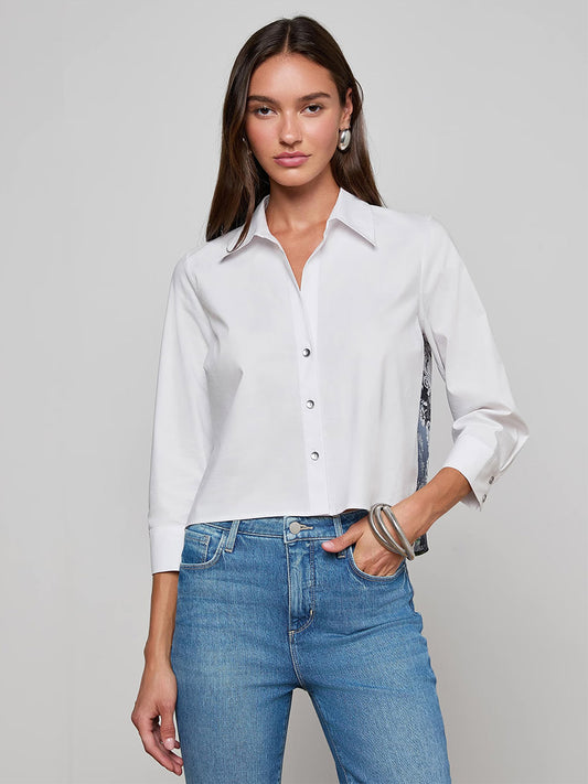 A woman wearing the L'Agence Fawn Panther Print Shirt in Ivory Multi Floral Panther Scarf and blue jeans stands against a plain light gray background.