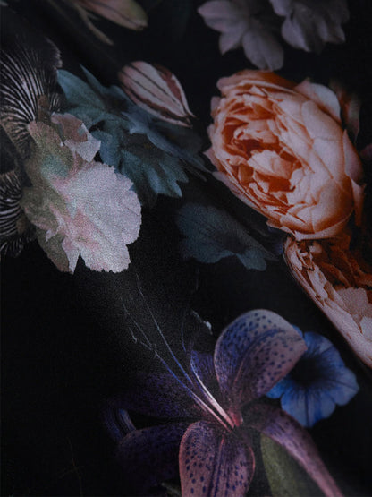 The L'Agence Gabriella Silk Camisole in Black Multi Vintage Oil Flower showcases a captivating dark floral print with roses, lilies, and other blossoms in orange, pink, and blue hues. It features adjustable straps for a comfortable and stylish fit.