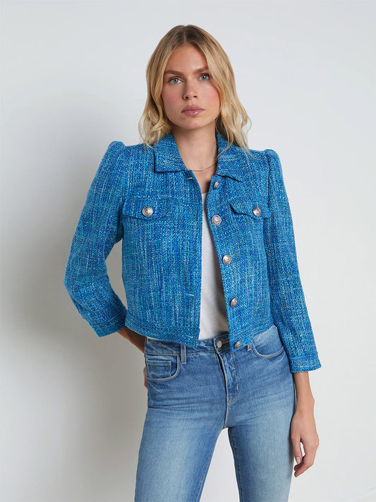 Sentence with product name: A woman with blonde hair named Kasey wearing a L'Agence Kasey Tweed Jacket in Caribbean Blue Multi Tweed with three-quarter sleeves and light blue jeans, standing against a plain white background.