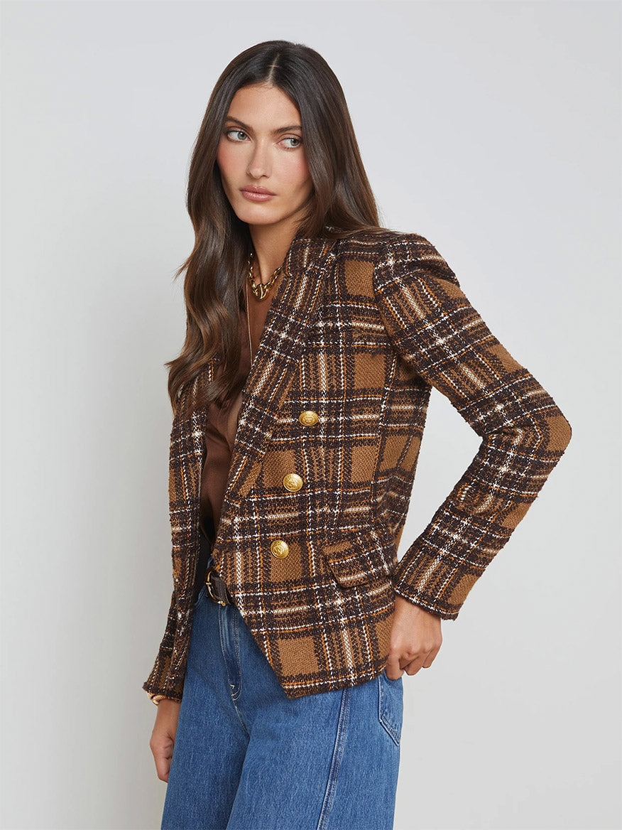 A person wearing L'Agence's Kenzie Blazer in blue brown/yellow plaid paired with blue jeans stands against a neutral background.