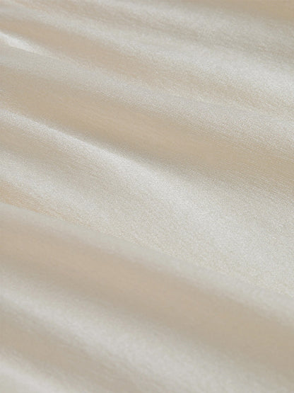 Close-up of smooth, cream-colored satin fabric with a subtle sheen and gentle folds, perfect for an elegant L'Agence Lexi Silk Camisole in Ivory.