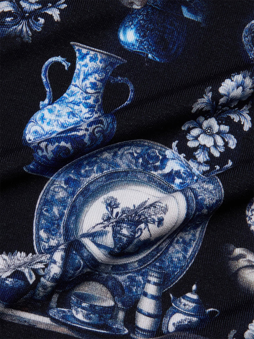 Close-up of the L'Agence Ressi Fitted Tee in Black/Blue Porcelain Print, featuring blue and white porcelain vases, plates, flowers, and decorative motifs on a dark background—ideal for a chic short sleeve look.