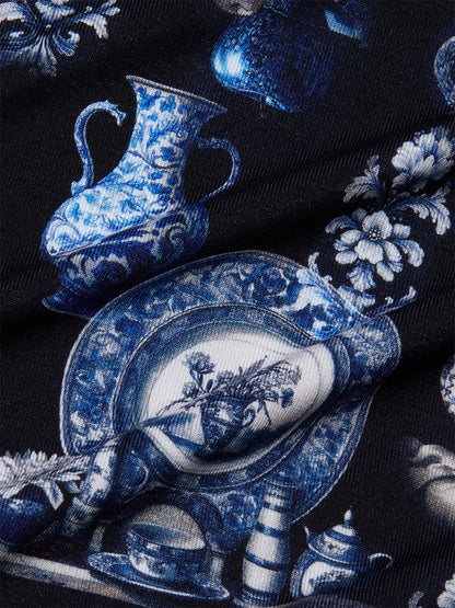 Close-up of the L'Agence Ressi Fitted Tee in Black/Blue Porcelain Print, featuring blue and white porcelain vases, plates, flowers, and decorative motifs on a dark background—ideal for a chic short sleeve look.