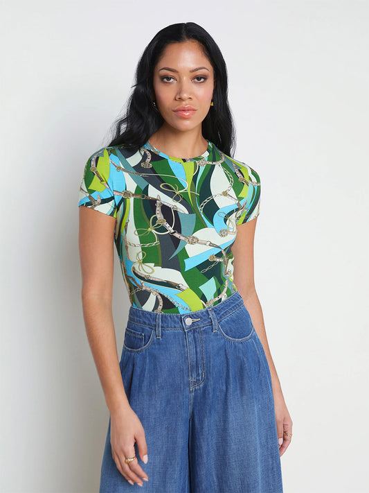 Woman standing in a studio, wearing a L'Agence Ressi Fitted Tee in Small Sea Green Belt Swirl top and high-waisted blue jeans.