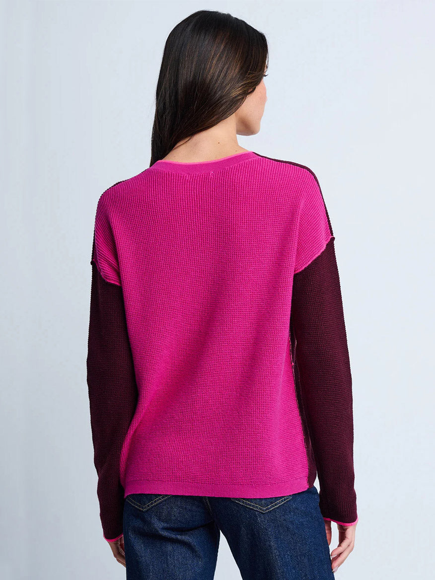 Wearing the Lisa Todd Around Town Sweater in Wine Hot Orchid—a bright pink and maroon colorblock cotton-cashmere sweater—and dark blue jeans, a person stands with their back to the camera.