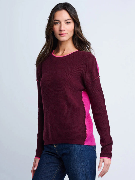 Woman wearing the Lisa Todd Around Town Sweater in Wine Hot Orchid with dark blue jeans, standing against a plain light background.