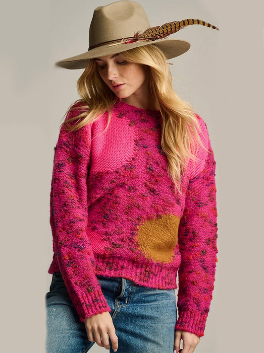 A woman wearing a cozy, multi-colored Lisa Todd Bolle Bolle Sweater in Pink Multi and a wide-brimmed fedora with a feather accent.