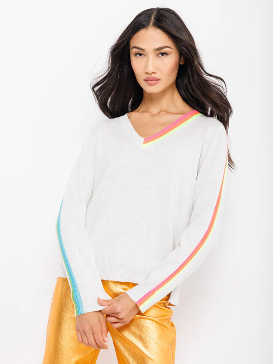 Woman posing in a Lisa Todd Color Code Sweater in Mineral with rainbow trim and gold pants, perfect for refreshing your Spring wardrobe.