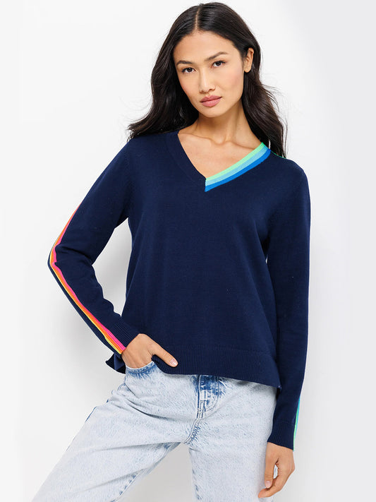 Woman wearing a Lisa Todd Color Code Sweater in Navy with colorful trim and light blue jeans for a relaxed fit, perfect for a Spring wardrobe.
