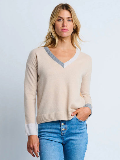 A woman wearing the Lisa Todd Color Wheel Sweater in Latte/Caramel and blue high-waisted jeans stands against a plain light background.