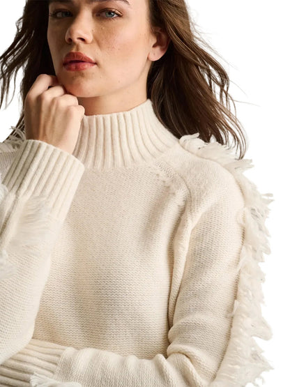 Woman wearing the Lisa Todd Fringe Benefits Sweater in Winter White, featuring a relaxed raglan silhouette and fringed sleeves, against a plain white background.