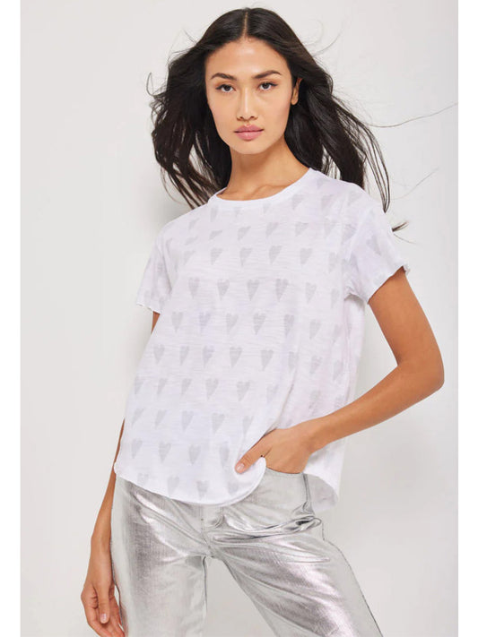 Woman posing in a white Lisa Todd Heart Hype Tee with screen print hearts and metallic silver pants.