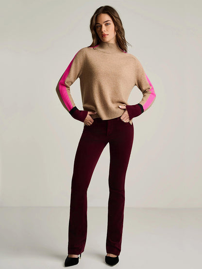 A woman stands in a neutral space wearing the Lisa Todd High Spirits Mock in Biscuit, paired with pink-striped sleeves, dark burgundy pants, and black shoes.