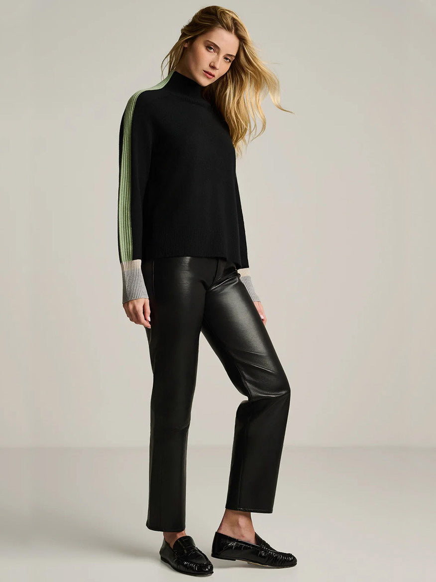 A woman wearing a Lisa Todd High Spirits Mock in Onyx with a relaxed raglan silhouette, lime green and grey striped sleeves, and black pants.