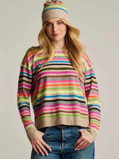 Woman wearing a relaxed fit multicolor knit striped sweater and the Lisa Todd Hype The Stripe Hat in Oat Multi Stripe, standing with one hand in her jeans pocket.