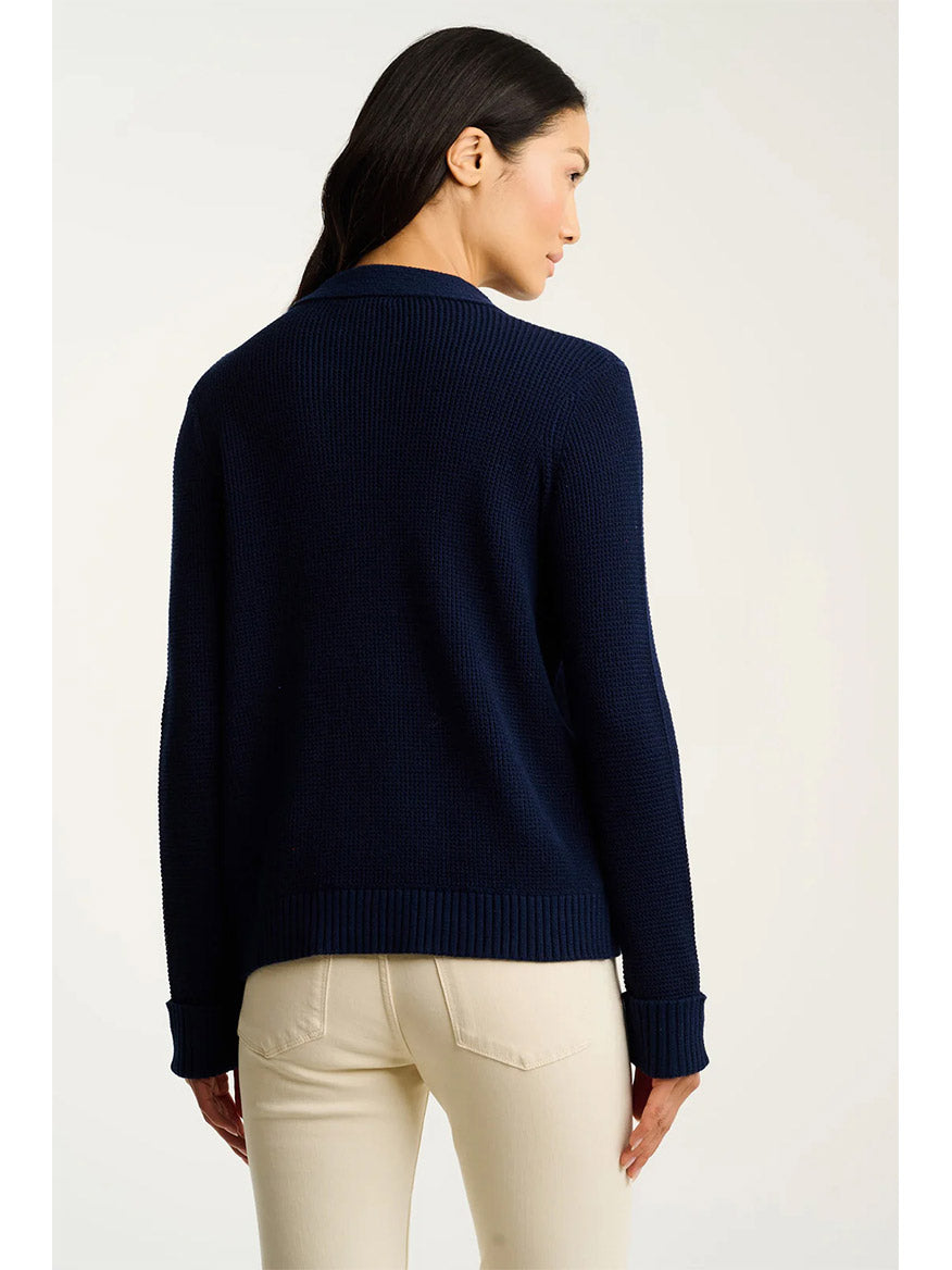 A woman stands with her back to the camera, wearing the Lisa Todd Knit Bliss Cotton Sweater in Navy and light beige pants against a plain background.