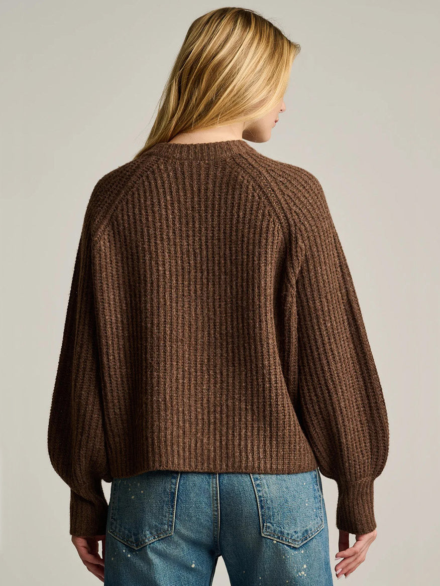 Back view of a person wearing a brown, ribbed-knit Lisa Todd Love Game Cardigan in Cocoa with long sleeves and blue jeans.