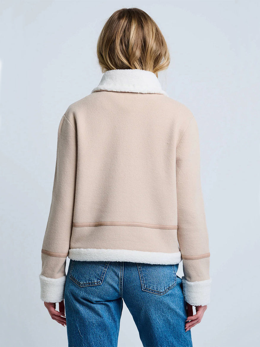 A person is shown from the back against a plain light background, wearing blue jeans and the Lisa Todd Moto Jacket With Sherpa Trim in Latte/Winter.