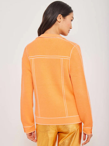 Woman wearing a Lisa Todd Pipe Dreamer Jacket in Orange Flash with white piping detail, viewed from behind.