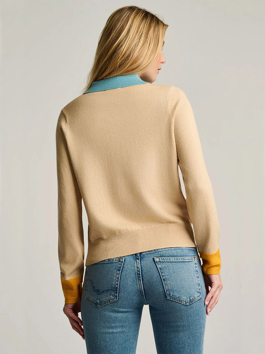 A person with long blonde hair, wearing the Lisa Todd Pop Posh Cotton Cashmere Polo in Sable paired with blue jeans, is shown from the back against a neutral background.
