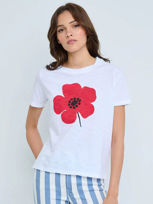 A woman wearing the Lisa Todd Posy Posse V-Neck in White, featuring a relaxed fit and large red flower print on the front, paired with blue-and-white striped pants.