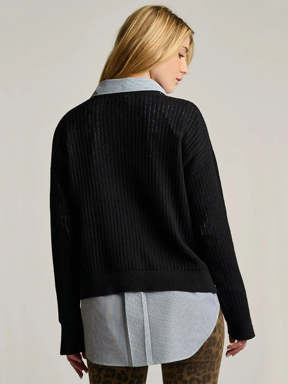 A person with long blond hair is shown from the back, wearing a relaxed fit Lisa Todd Power Stitch Cotton Pullover in Black over a light blue collared shirt and leopard print pants.