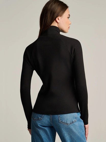 A person wearing a black, slim fit Lisa Todd Pure Pima Rib Turtleneck.