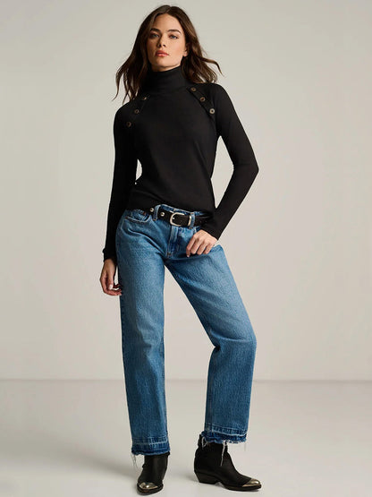 A black Lisa Todd Pure Pima Rib Turtleneck with button details at the shoulders, worn with blue jeans and black boots.