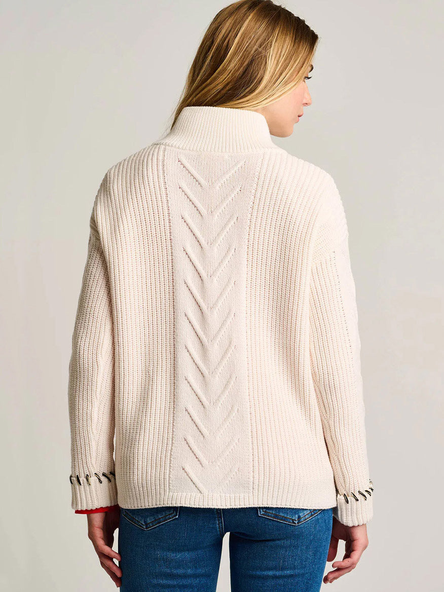 A woman with long blonde hair is shown from the back, wearing the Lisa Todd Rule Bender Sweater in Snow and blue jeans.