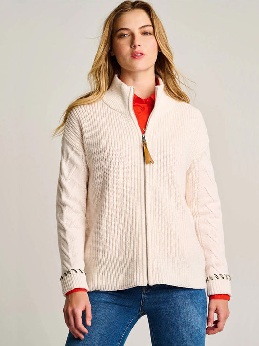 A woman wears the Lisa Todd Rule Bender Sweater in Snow over a red shirt and blue jeans, standing facing forward against a neutral background.
