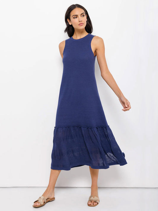 Woman posing in a sleeveless Lisa Todd Shifty Dress in Indigo with an open stitch flared bottom hem against a white background.