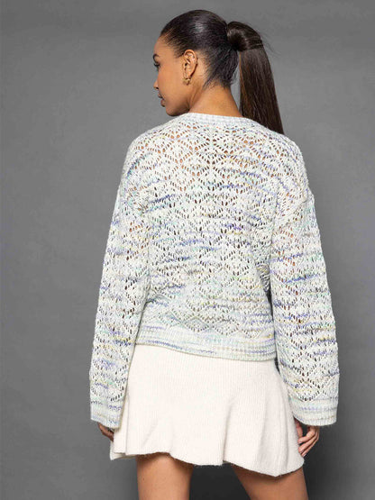 A person with a long ponytail, wearing the Lisa Todd Soft Landing Sweater in Seaglass paired with a white skirt, is facing away against a gray background.