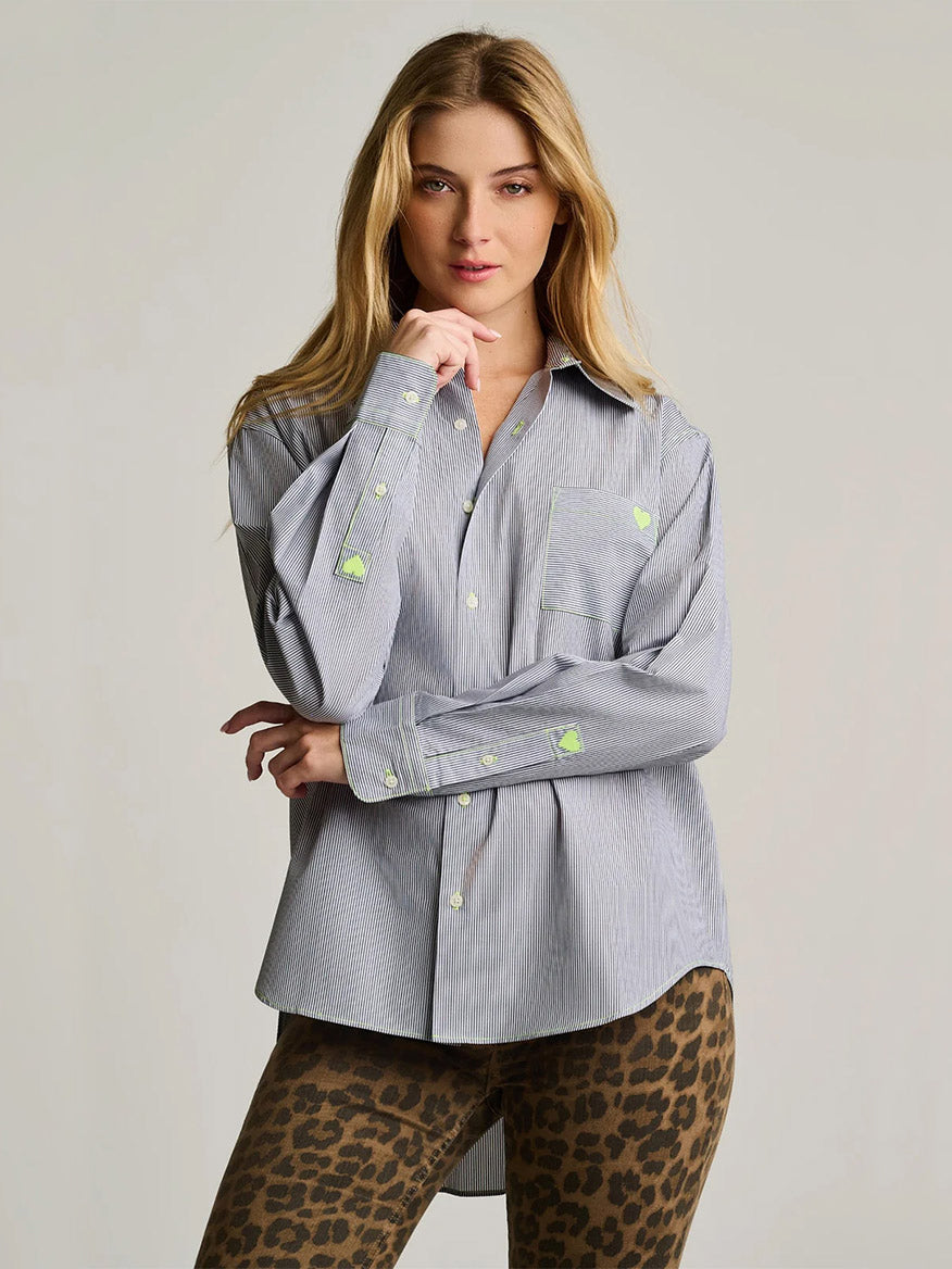 Woman stands facing forward in the Lisa Todd Stripe It To Me shirt in black and white—an oversized fit button-down expertly tailored from cotton—with neon green patches, paired with brown leopard print leggings, against a plain light background.