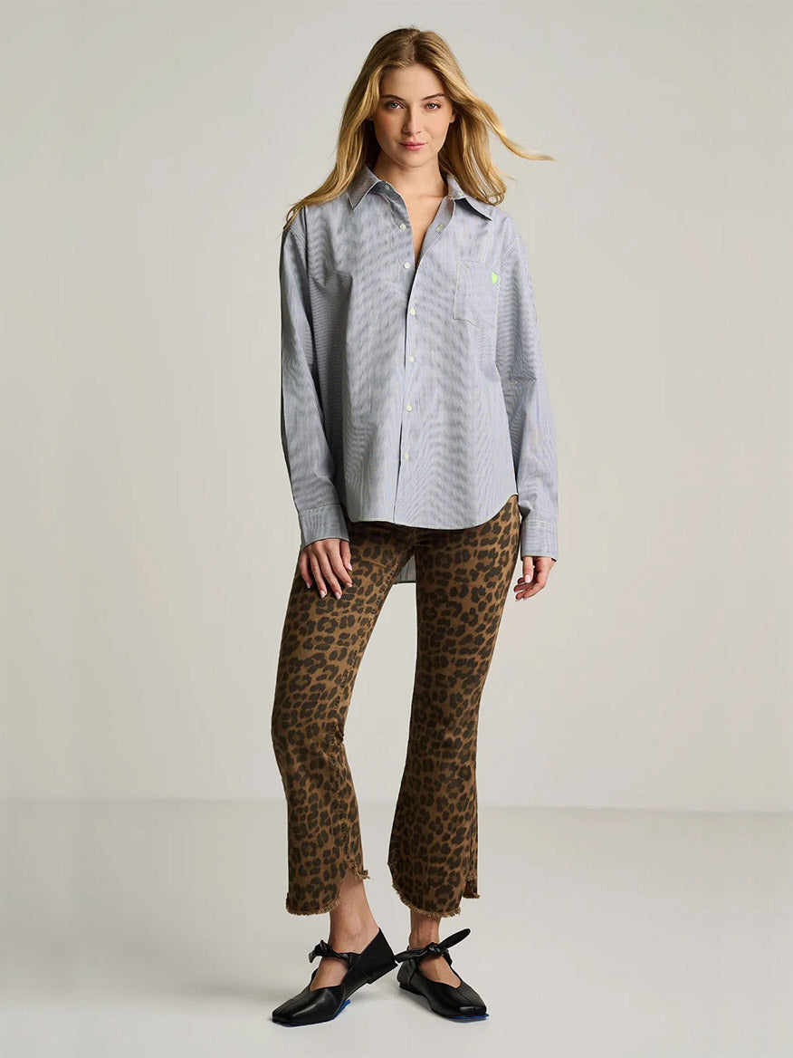 A woman stands in a studio wearing the Lisa Todd Stripe It To Me shirt in Black/White, styled with brown leopard print pants and black flats.