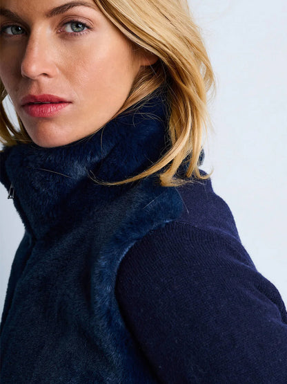 Close-up of a woman with blonde hair wearing the Lisa Todd Teddy Faux Fur Knit Jacket in Navy, looking slightly to the side against a light background.