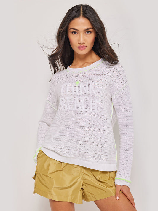 Woman posing in a Lisa Todd Think Beach Long Sleeve Crew Sweater in White and yellow shorts.