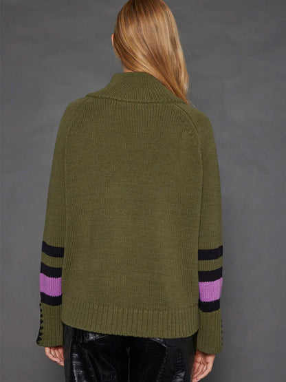 A person with long hair is seen from the back, wearing the Lisa Todd Unzipped Sweater in Eden, featuring a chunky knit design with black and purple stripes on the sleeves.