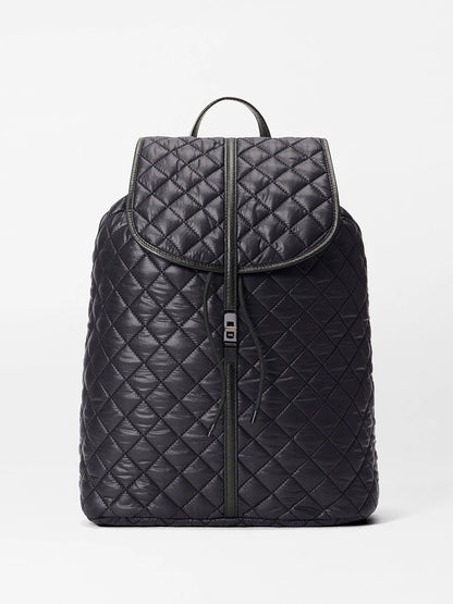 The MZ Wallace Astor Backpack in Black Oxford is a quilted laptop backpack with gunmetal hardware, flap closure, front zipper, and top handle—shown on a plain white background.