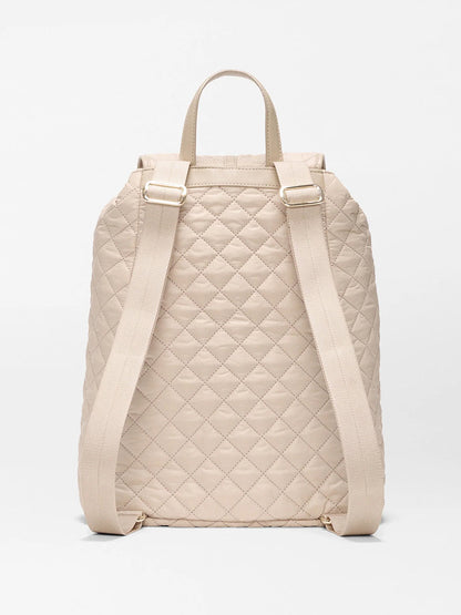 The MZ Wallace Astor Backpack in Buff Oxford is a beige quilted laptop backpack shown from the back, with padded straps, a top handle, and a diamond stitch pattern.